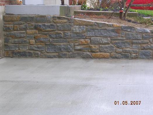 Split fieldstone retaining wall and concrete driveway / Anderson